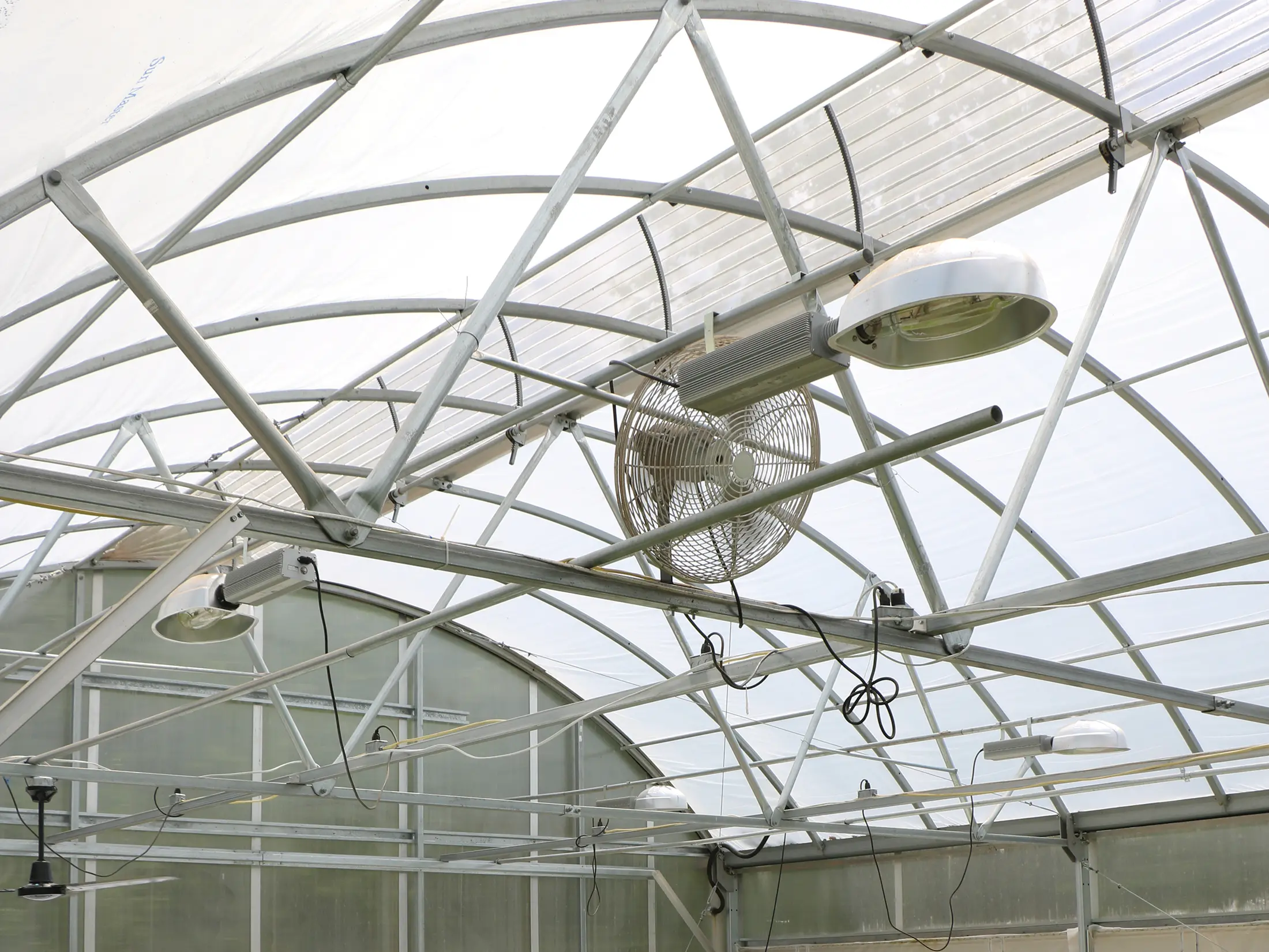 supplemental light fixture and air circulation fan inside year-round greenhouse