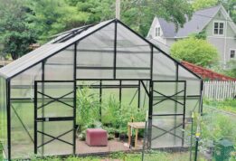 Front of a GrowSpan Estate Deluxe Small Greenhouse surrounded by a garden