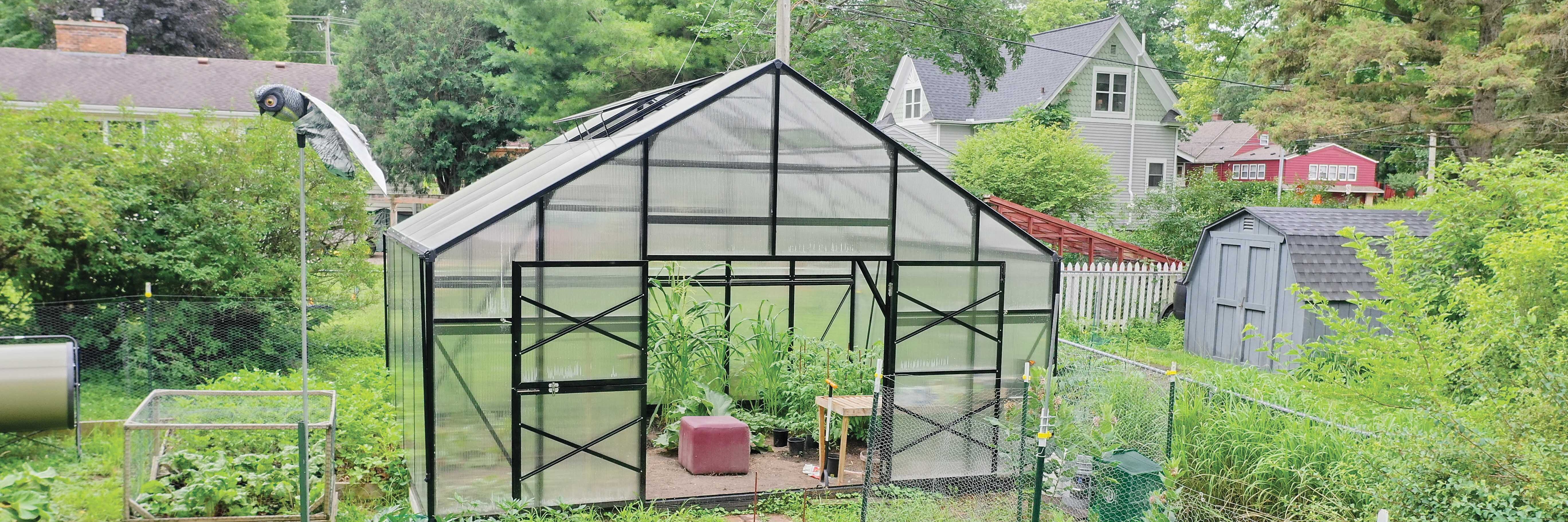 Front of a GrowSpan Estate Deluxe Small Greenhouse surrounded by a garden