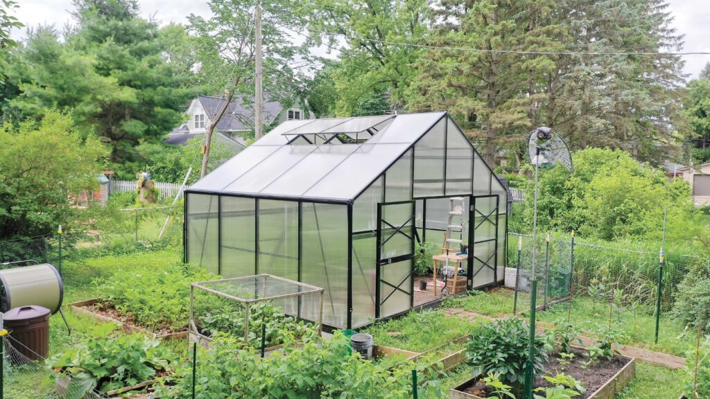 Side of a GrowSpan Estate Deluxe Small Greenhouse surrounded by a garden
