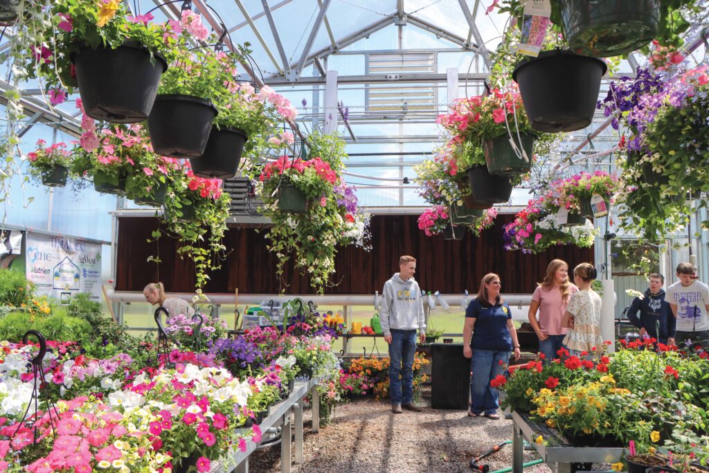 A teacher instructs students in the back of a GrowSpan Series 2000 Greenhouse